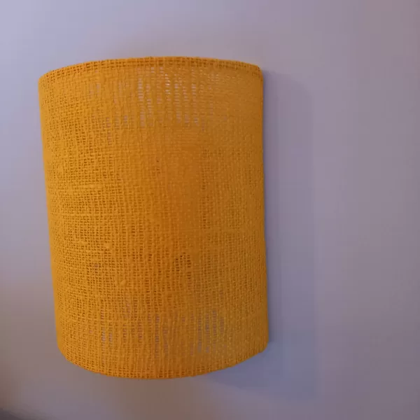 Bra tipa sienas lampa no rupja pinuma linu auduma un caurspīdīgu plastikātu.
